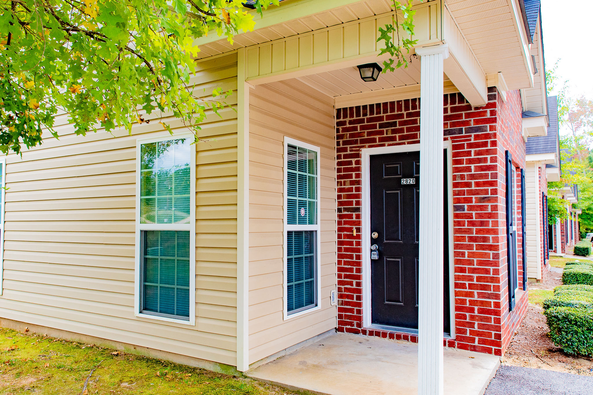 the front porch of a home with a black door